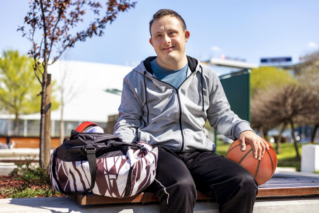 a person sitting on a bench and holding a basketball is smiling at the camera